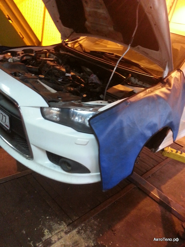 Белый Mitsubishi Lancer Evolution X с открытым капотом на ремонте в автосервисе — автосервис автотело.рф
