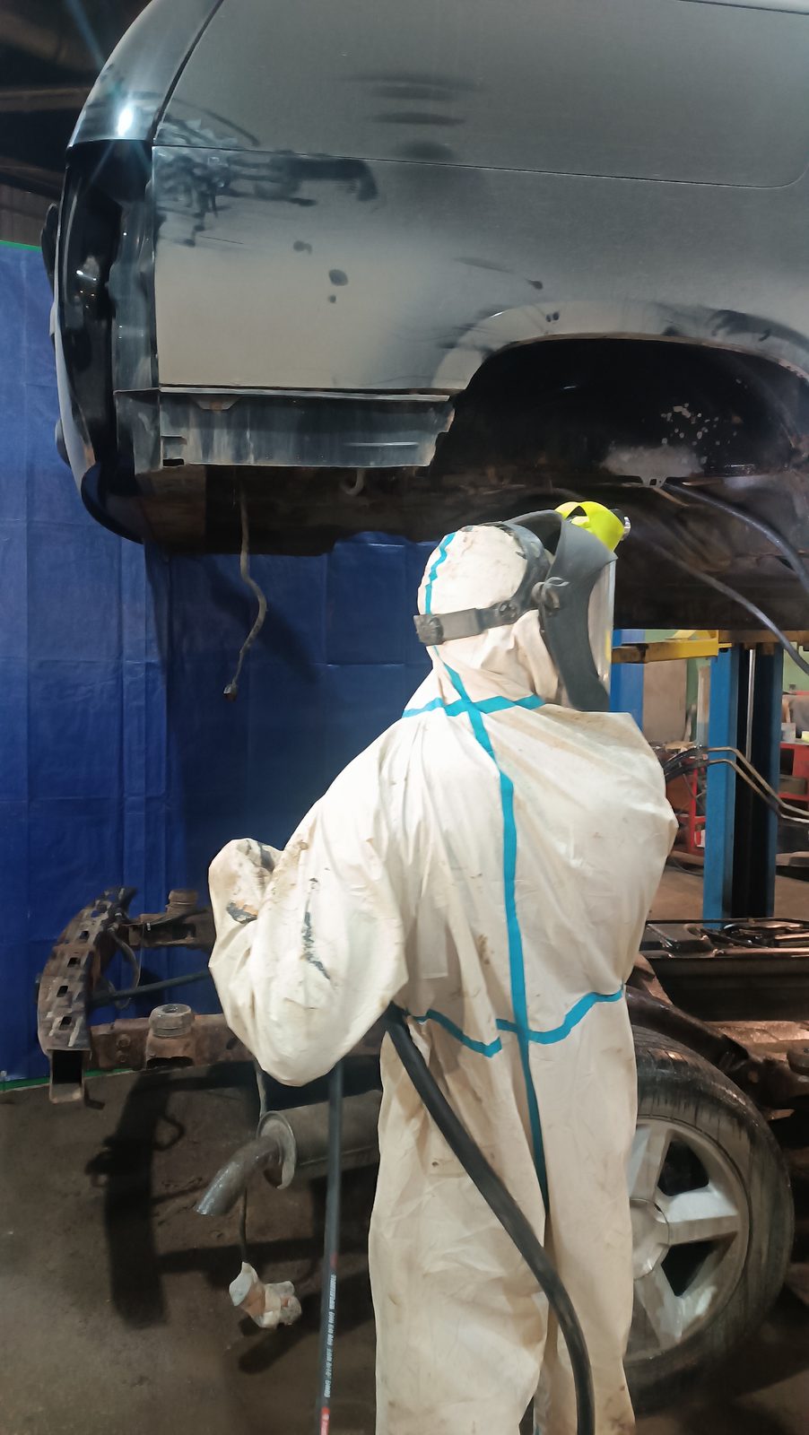 Оператор в защитном костюме выполняет АкваБласт днища автомобиля на подъёмнике — автосервис автотело.рф